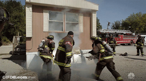 Firefighters In Front Of Mobile Home With Smoke GIF