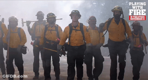 Firefighters Standing In Front Of Playing With Fire Sign GIF