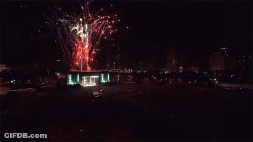 Fireworks Are Displayed In The Night Sky Above A Large Crowd GIF