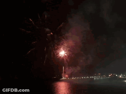 Fireworks Are Displayed Over A Body Of Water In The Night Sky GIF
