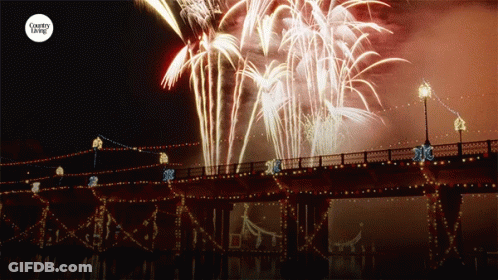 Fireworks Are Displayed Over A Bridge With The Words Country Living On The Bottom GIF