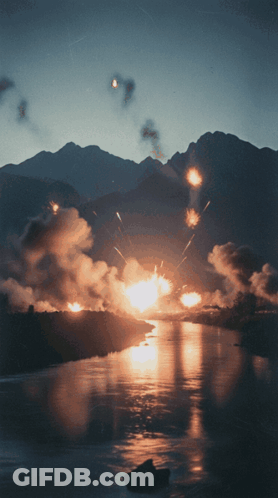 Fireworks Exploding Over Water In Front Of Mountains GIF