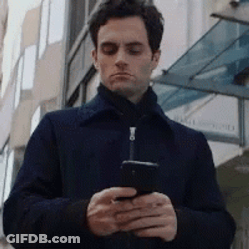 Focused Joe Goldberg Holding Cellphone GIF
