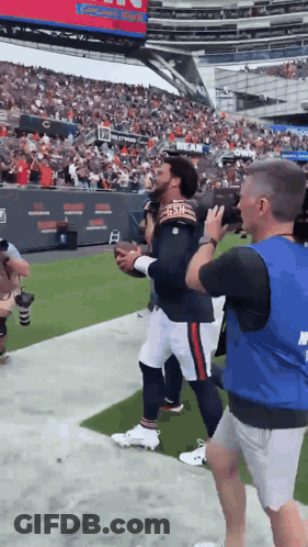 Football Player In Bears Jersey Escorted By Security Guard GIF