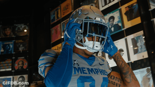 Football Player In Memphis Jersey And Helmet In Front Of CD Wall GIF