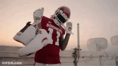Football Player In Sooners Jersey Holding Shoes GIF