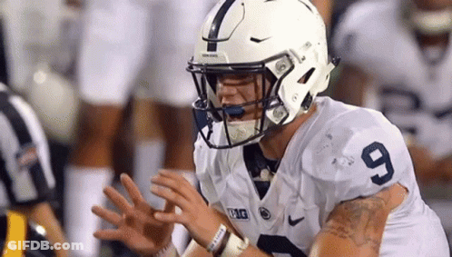 Football Player In White Helmet 9 Jersey Sitting On Field With Hands Outstretched GIF