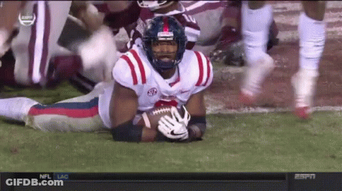 Football Player Lying On Field Holding Ball With NC Helmet GIF