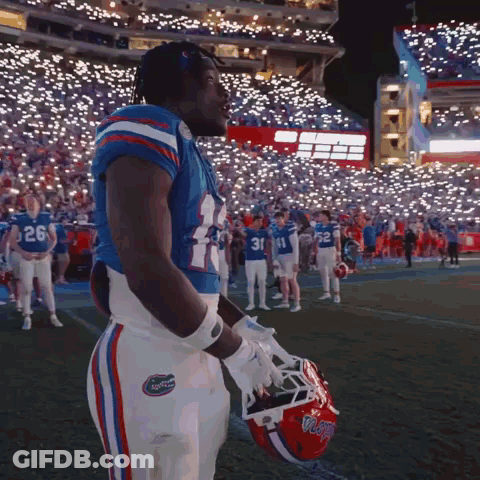 Football Player Number 24 Holding Helmet In Front Of Crowd GIF