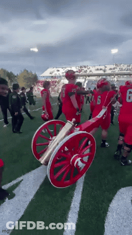 Football Players Holding Cannon On Field GIF