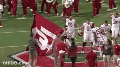 Football Players Holding Large Red And White Flag GIF