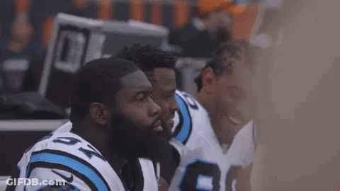 Football Players Huddle On Sidelines GIF