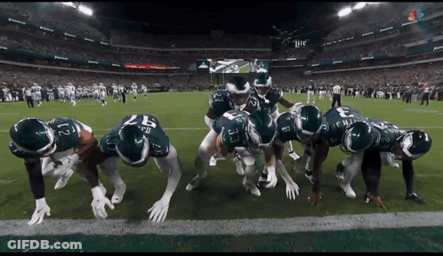 Football Players Huddled In Stadium GIF