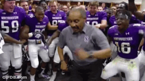 Football Players In Purple Uniforms Dancing With Man In Grey Shirt GIF