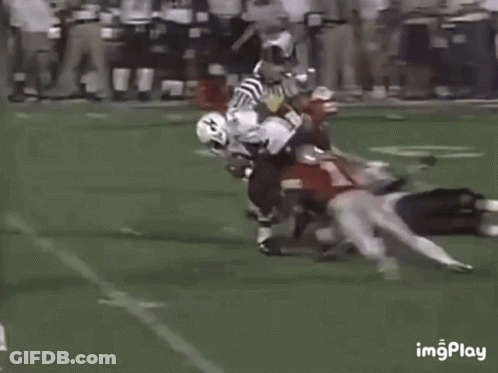 Football Players Playing On Field With One Laying Down GIF