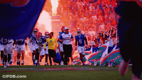 Football Players Running On Field With Flames GIF