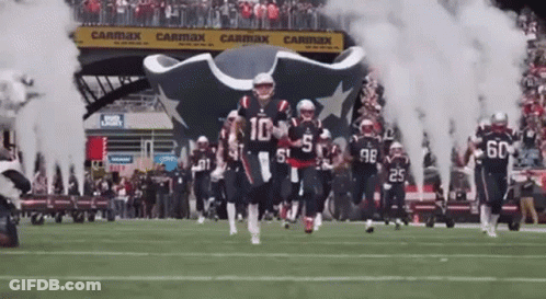 Football Players Running On Field With Smoke From Tunnel GIF
