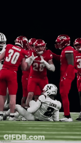 Football Players Standing Around Injured Player On Field GIF