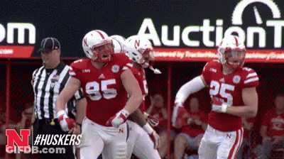 Football Players Standing In Front Of Auction Sign GIF