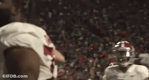 Football Players Standing On Field Holding Football GIF