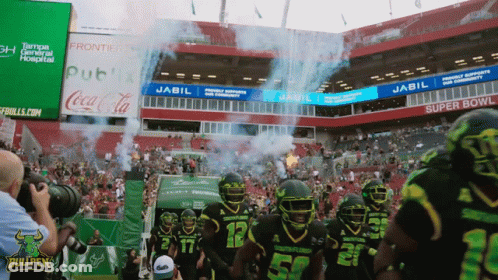 Football Players Walking Into Stadium Sponsored By Jabil And Coca-Cola GIF