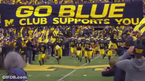 Football Team Running With Go Blue M Club Banner GIF