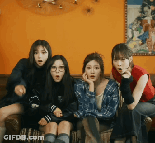 Four Girls Are Sitting On A Couch With One Wearing A Plaid Shirt With The Letter B On The Front GIF