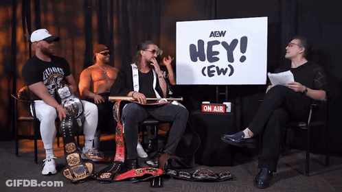 Four Men Sitting In Front Of Hey (Ew) Sign GIF