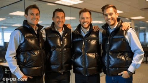 Four Men Wearing Black Vests Are Posing For A Picture Together GIF