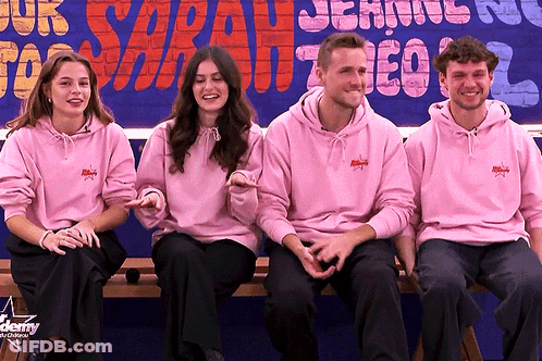 Four People In Pink Hoodies Sitting At Sign GIF