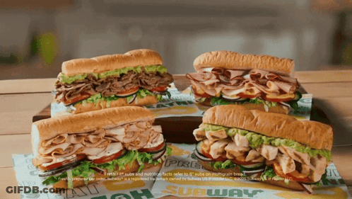 Four Subway Sandwiches Are Sitting On A Table GIF