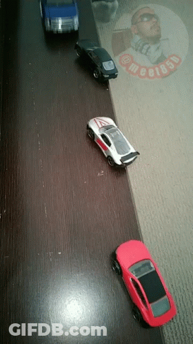 Four Toy Cars Lined Up With Man In Sunglasses And Text Megi85p GIF