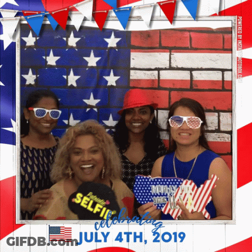 Four Women Pose For A Picture In Front Of An American Flag On July 4Th 2019 GIF