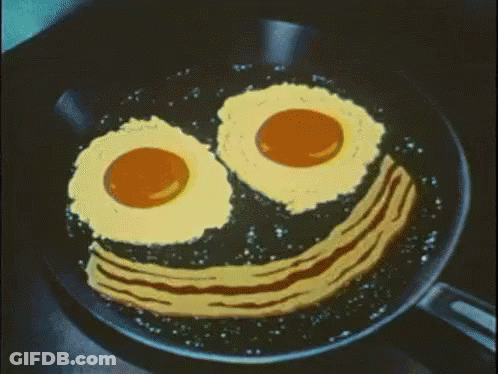 Fried Eggs And Bacon In A Frying Pan With A Smiley Face Drawn On It GIF