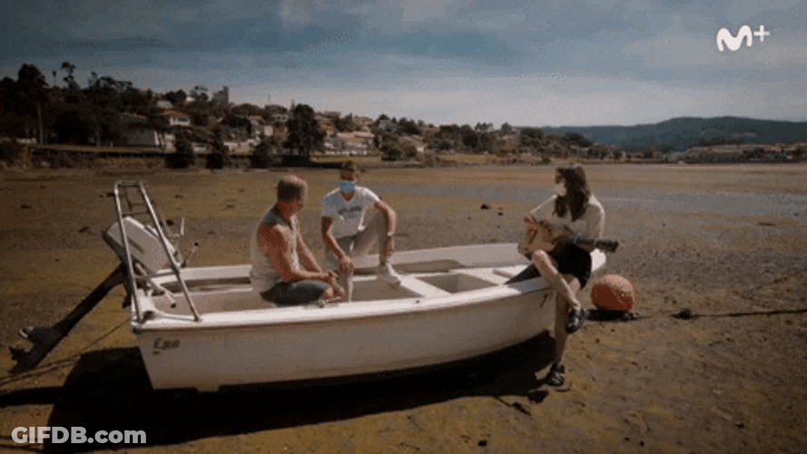 Friends Sitting On Skiff Talking Near Shore GIF