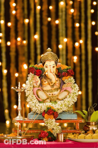Ganesha Statue On Table With Flowers GIF