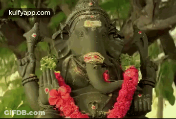 Ganesha Statue Sitting Under Tree With Red Flower Garland GIF