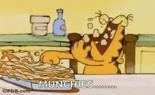 Garfield Is Sitting At A Table Eating A Piece Of Lasagna . GIF
