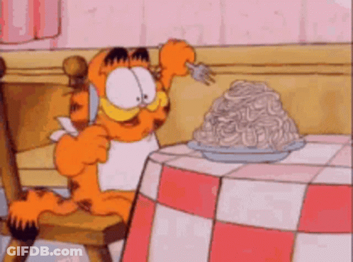 Garfield Is Sitting At A Table Eating Spaghetti With A Fork .. GIF