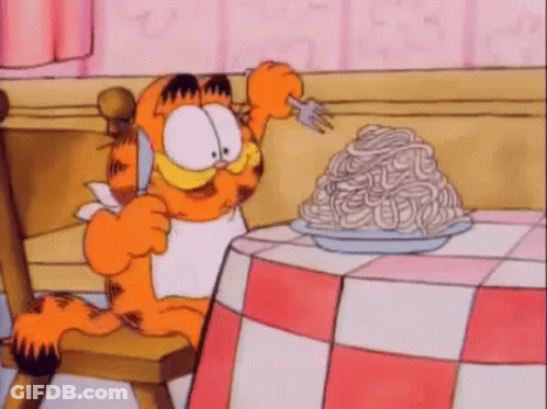 Garfield Is Sitting At A Table With A Plate Of Spaghetti On It . GIF
