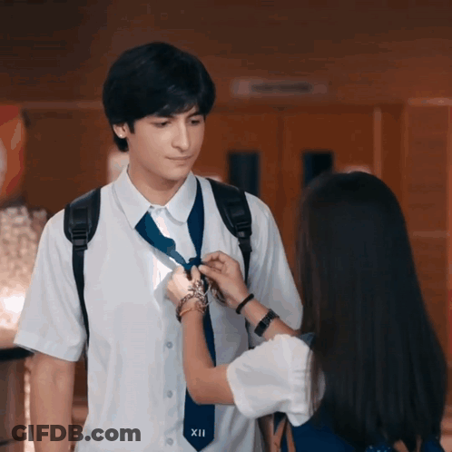 Girl Adjusting Boy's Tie With Number XII GIF