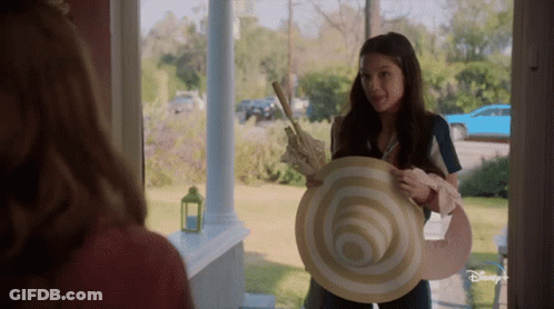 Girl Holding Large Hat In Front Of Disney Plus Door GIF