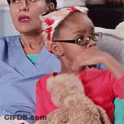 Girl Holding Teddy Bear Next To Woman With Glasses GIF