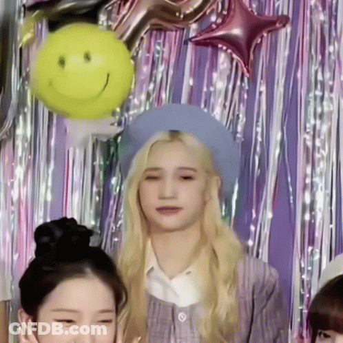 Girl In Blue Hat Standing In Front Of Balloons GIF