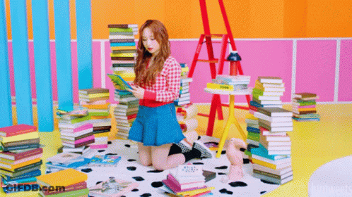 Girl In Blue Skirt Reading Surrounded By Book Stacks GIF