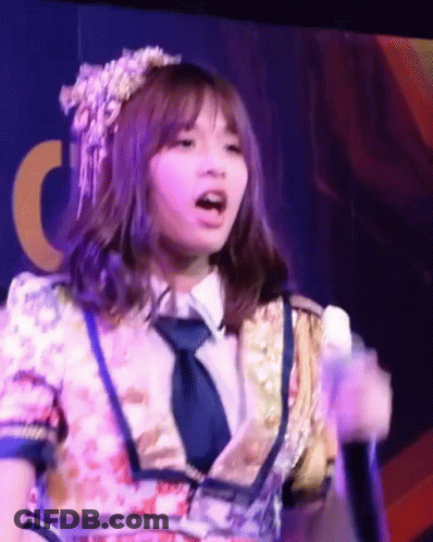 Girl In Floral Dress And Tie Singing Into Microphone GIF