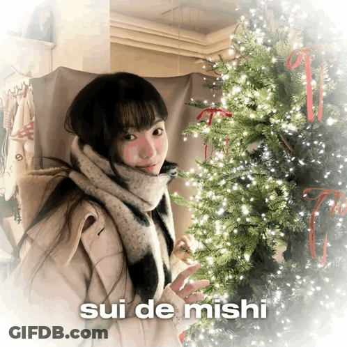 Girl In Front Of Christmas Tree With Sui De Mishi GIF