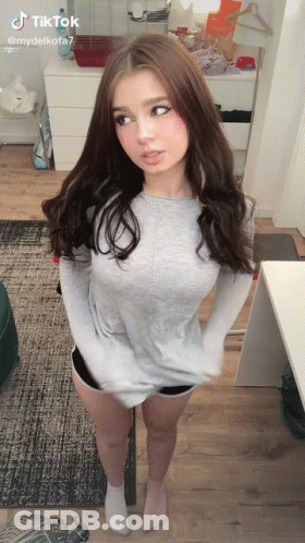 Girl In Grey Shirt And Shorts With Hands In Pockets GIF