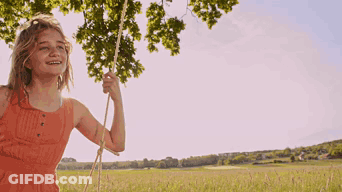 Girl In Orange Dress Swinging On Rope GIF