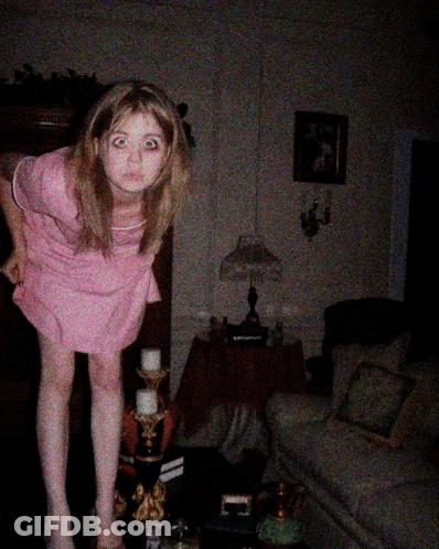 Girl In Pink Dress Standing In Dark Living Room GIF